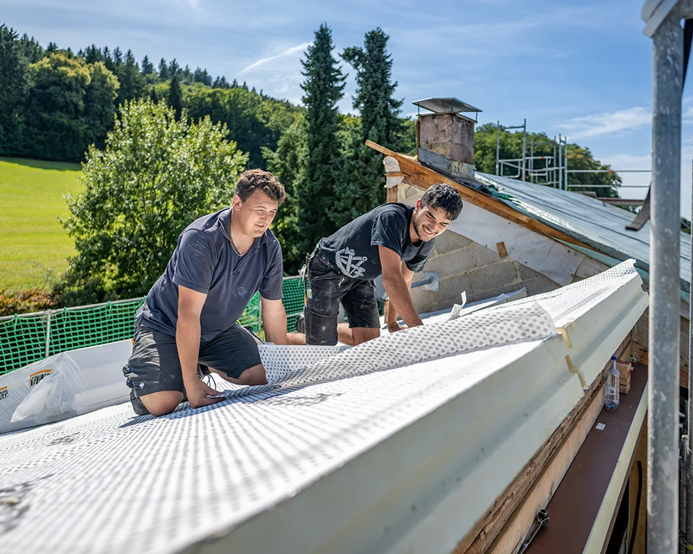 Mitarbetende der Firmal Gerlach Gebaeudetechnik bei der Arbeit auf einem Dach. 